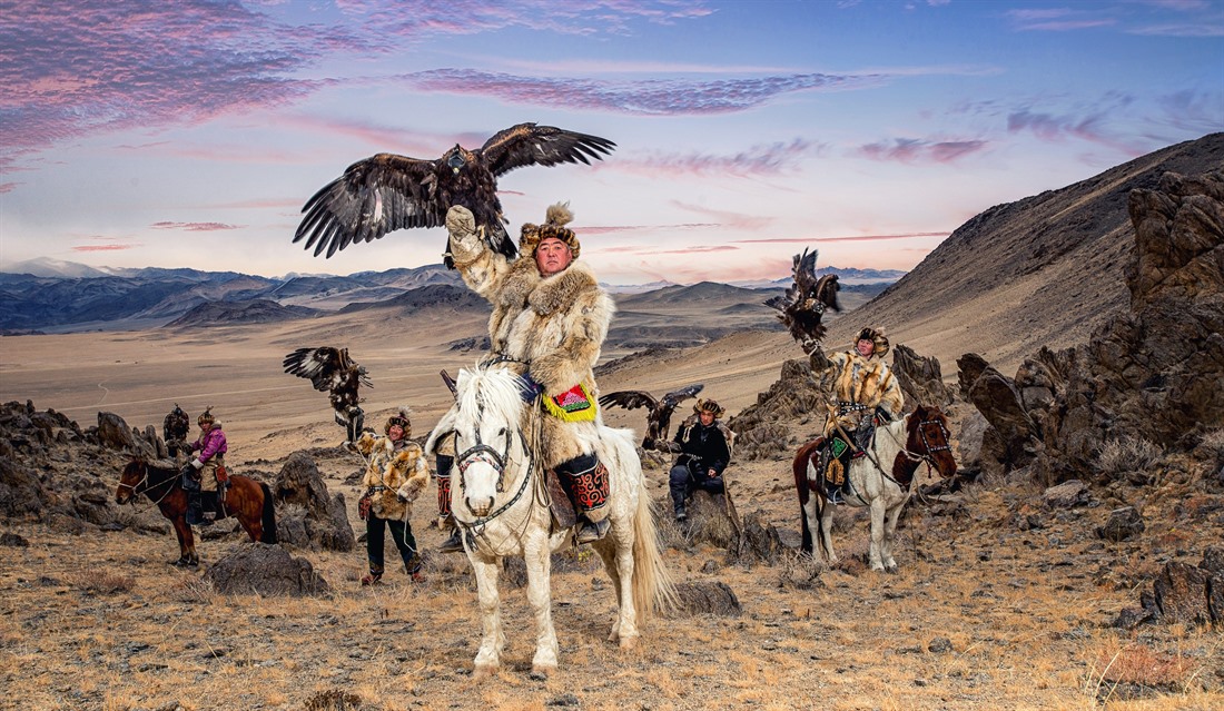 A group of eagle hunters proudly lift their eagles aloft. © Shutterstock/Chanwhit Whanset