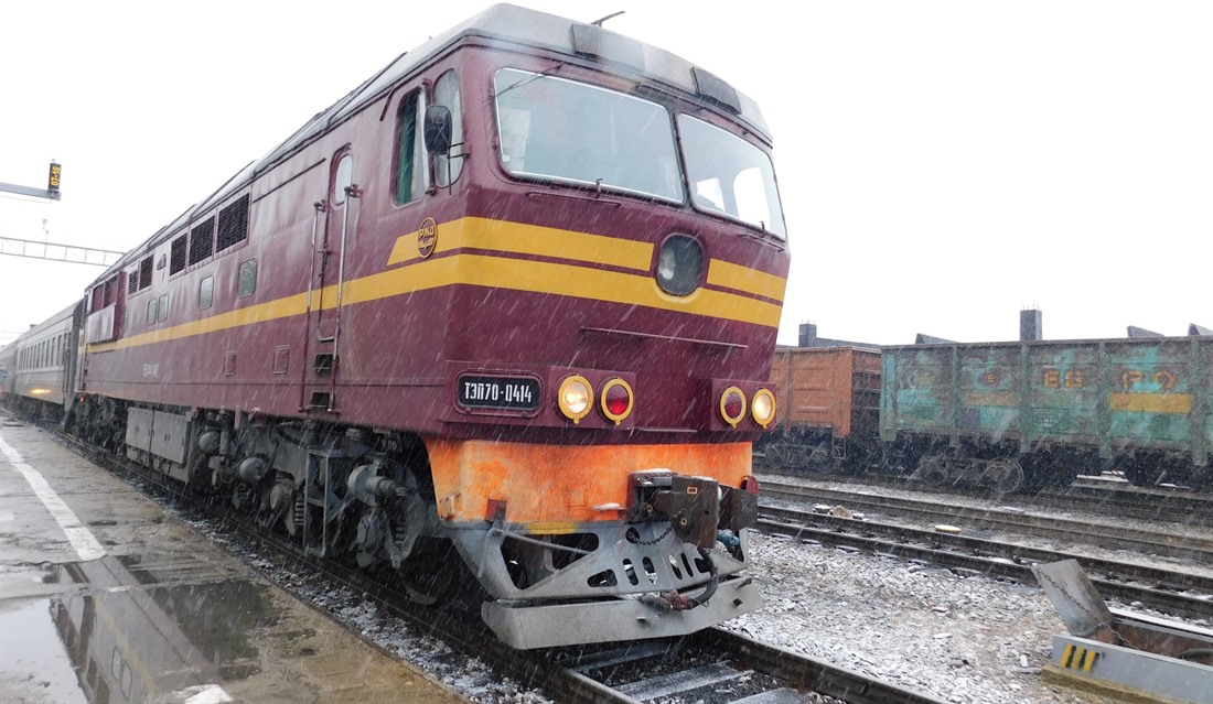 A train waits in the snow at a platform on the BAM Railway