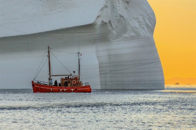 Tourist boat sailing near iceberg